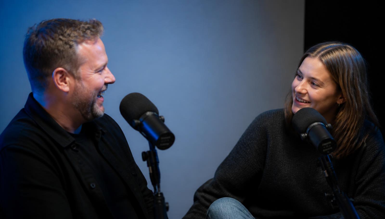 A host and guest laughing mid-conversation during a podcast recording